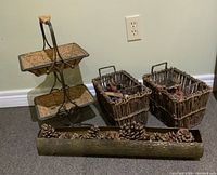 Full view of the two-tier metal basket stand, two twig and vine baskets, and metal centrepiece with dried botanicals and pine cones.
