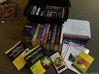 Photo of multiple books spanning novels by Margaret Atwood, Stephen King, Iain M. Banks, Ellen Hopkins, John Steinbeck, 'Dummies' programming and HTML books, and file holder totes.