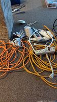 Overview photo showing three orange extension cords and four white power bars with multiple outlets.