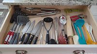 Drawer with assortment of kitchen utensils including BBQ tools, knives, mixing tools and spatulas