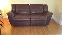 Front view of two-seat brown leather reclining sofa showing overall appearance.