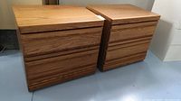 Pair of oak veneer night stands side by side showing front and top view with drawer handles recessed into the drawer fronts.