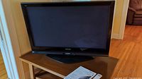 Front view of Panasonic Viera 42 inch plasma TV on oval swivel stand with instruction manual booklet on table.