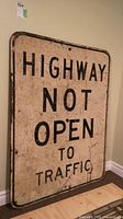 Full view of the wooden highway sign with black text on white background showing its overall condition and size.