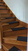 Black rectangular rubber anti-slip stair runners placed on wooden stairs, showing the textured surface and placement on stair treads.