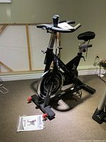 Front side view of entire bike resting on carpet with manual on floor