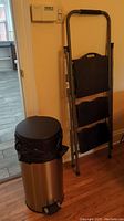 Step ladder leaning against wall next to trash can