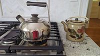 Metal kettle and glazed pottery teapot on stove and counter