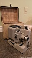 Full view of the vintage Eumig projector in front of its open carrying case showcasing the item's overall condition and accessories.