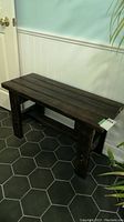 Side view of the dark stained wood hall bench showing rectangular legs, horizontal brace and slatted top surface.