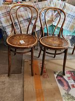Four wooden chairs with round carved seats and curved backs in a garage setting.