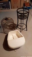 Footbath massager, plant stand, and wire bird cage grouped together on floor