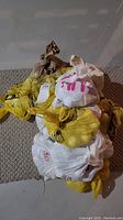 Image showing a stack of 24 tied plastic bags in yellow, white, red, and beige colors containing golf balls.
