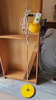 Full view of lamp showing yellow base, chrome pole, and yellow adjustable lamp shade with electrical cord wrapped around top.