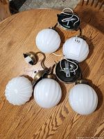 Set of three white glass globe wall hanging light fixtures with brass-tone mounts, showing globes and wiring.