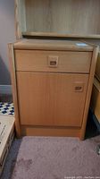 Front view of one teak night table showing drawer and cabinet door with square recessed handles