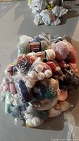 Large pile of assorted balls of Bernat worsted wool yarn in various colors, some still in plastic bags