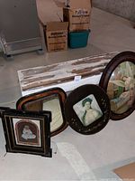 White distressed wooden bench with multiple antique photo frames and a mirror placed on the floor.