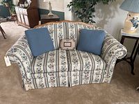Front view showing floral upholstery and blue pillows.