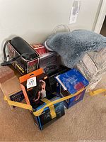 Overview of miscellaneous items bundle showing resistance band, boxes, bath rug, and basket taped together