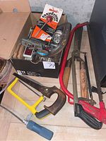 Photo showing various hand tools including saws, a clamp, a file, and a jar of screws.