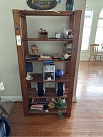 Front view of wooden shelving unit with multiple shelves and some items on it.