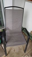 Close-up of one patio chair showing black metal frame, high back with mesh grey fabric seating and backrest.