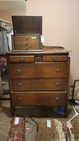 Front view of a vintage wooden dresser with jewelry box on top and some rugs on the floor in front