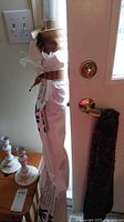 Bolt of fabric wrapped in white paper, standing upright against a door, showing the top with fabric visible and wrapping around a tube.
