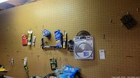 Pegboard wall with various wall hardware and small tools hanging in their packaging or attached