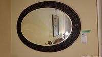 Oval mirror with carved wooden frame reflecting room interior.