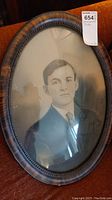 Oval framed antique portrait photo showing young man and tiger wood grain frame details.