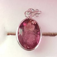 Front view of oval faceted pink tourmaline pendant set in 14K white gold with decorative bail.