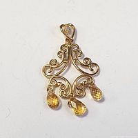 Front-facing image of the 14K yellow gold pendant with three yellow sapphire drop gemstones displaying decorative scrollwork.