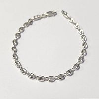 Silver oval link chain bracelet arranged in a circular shape on white background, showing overall design and length.