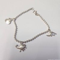Clear photo of the silver bracelet with dinosaur charms, showing details of charms and chain.