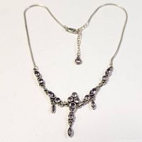 Full view of the silver necklace with amethyst stones laid out flat showing chain and clasp.