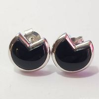 Front view of pair of silver stud earrings with polished black onyx stones and unique V-shaped notch design at top edge.