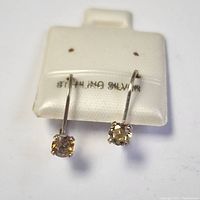 Front view of sterling silver earrings with round citrine stones on white card stamped 'STERLING SILVER'.