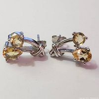 Pair of silver earrings with two citrine gemstones each, shown from front angle.