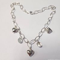 Full view of silver 16-inch chain necklace with three silver heart charms and two genuine gemstone charms.