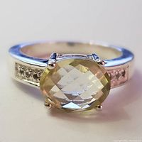 Front view of the silver ring featuring an oval cut lemon quartz held by four prongs and small accent stones embedded in the band sides.
