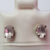 Front view of both oval moonstone sterling silver stud earrings on a white holder.