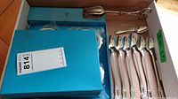 Full view of the collection in original box including spoons, tongs, coasters, and opener