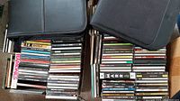 Two carry cases and two boxes filled with various stacked CDs including rock, punk, alternative, reggae, and classical artists