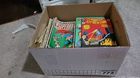 Cardboard box containing stacked vintage comics including 'ATF America ATP New York' and Superboy