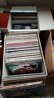 Boxes filled with assorted vinyl LP records showing various album covers, including Grease soundtrack