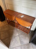 Two wooden side tables with drop leaves folded down, showing the flat top view and base design.