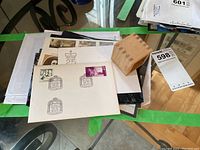 Multiple FDC envelopes in protective sleeves, plus a small wooden box on a glass table