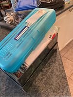 Blue plastic storage container on top of a metal box, containing stamps and other materials.